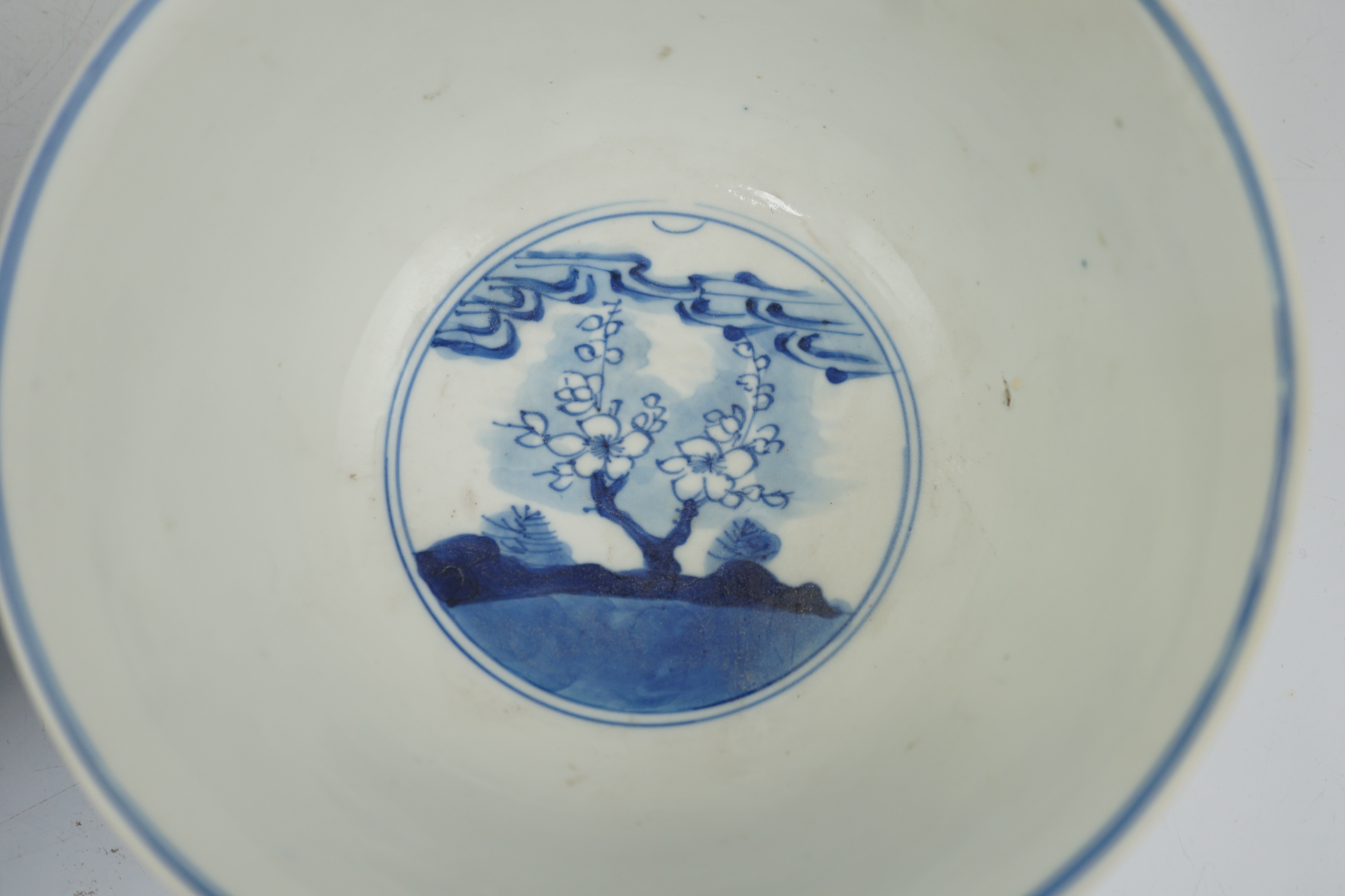 A near pair of Chinese blue and white ‘birds’ bowls, Kangxi period, one bowl restored